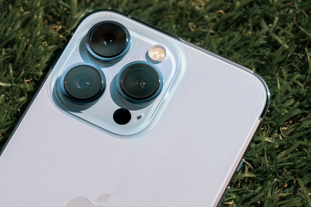 about-us Detailed close-up of smartphone camera lenses on green grass background.