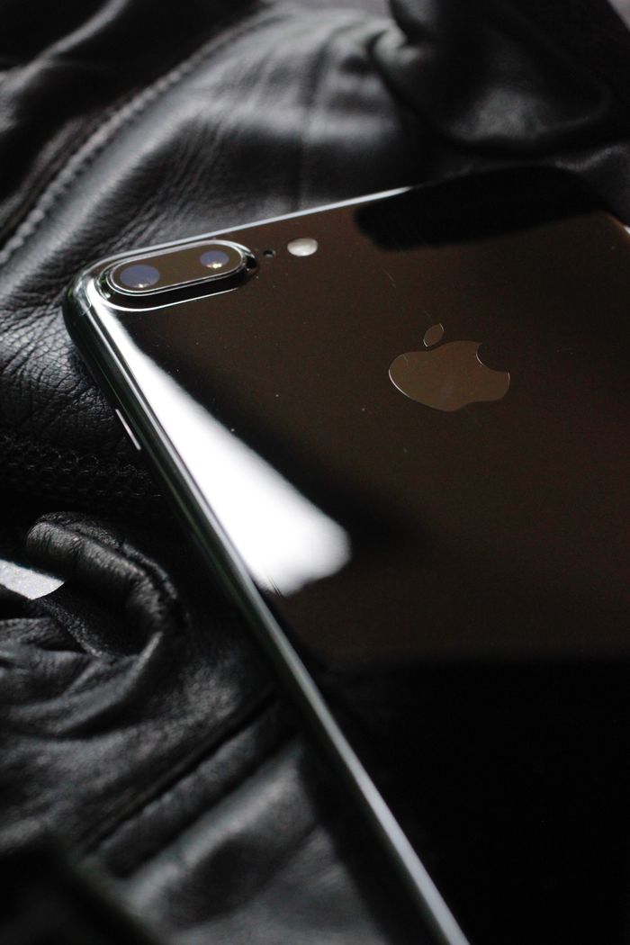 services-02 Close-up of a shiny black smartphone on a textured leather surface.
