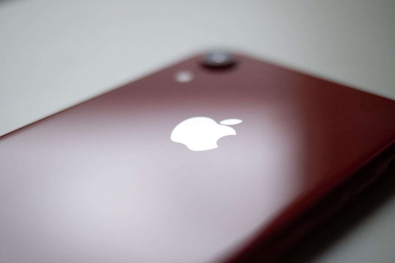 A red smartphone showcasing a sleek design with its iconic logo, focused on technology.